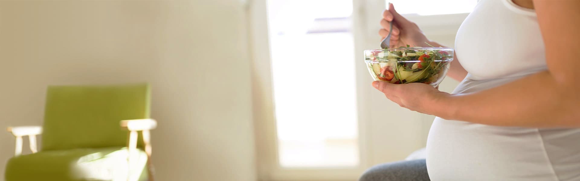 Pregnant woman on healthy diet holding salad