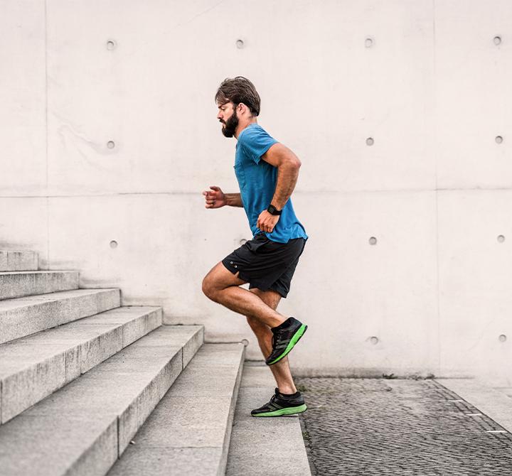 Sporty man running up steps in urban setting