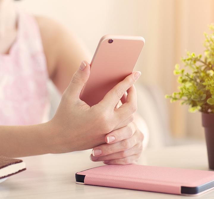 Woman in summer cafe holding a pink phone