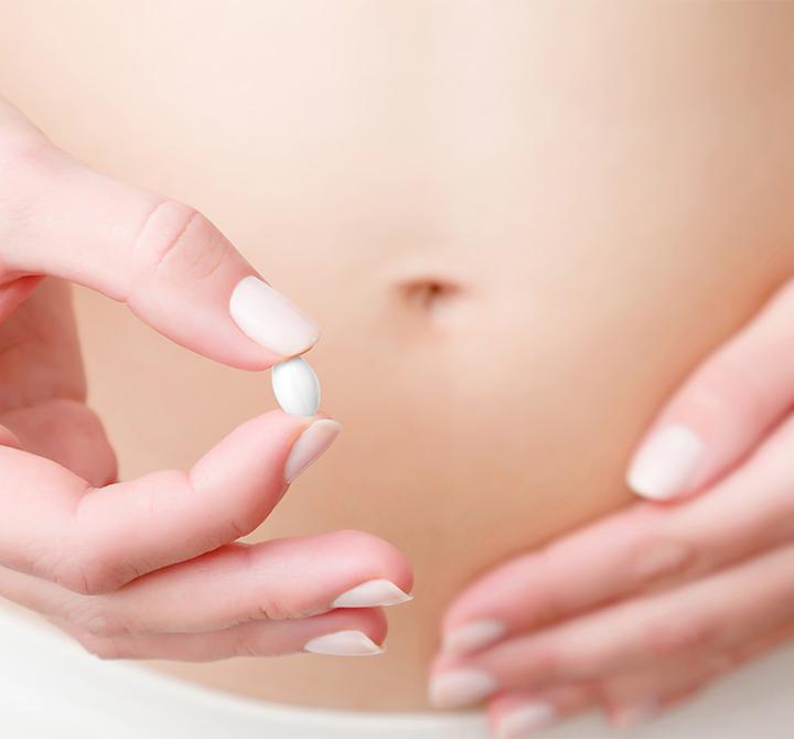 Young woman's hand holding pill